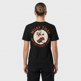 T-shirt unisexe vu de dos, avec un écusson vintage montrant un combattant de Muay Thaï en garde, aux mains bandées de rouge, dans un médaillon crème entouré du texte « Muay Thai – Art of Eight Limbs ». – photo studio femme