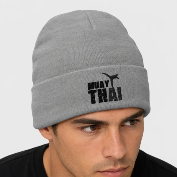 Bonnet en maille avec, brodée devant, une silhouette noire de combattant de muay-thaï en high kick au-dessus des lettres « MUAY THAI » à effet craquelé. – photo studio