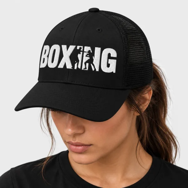 Casquette trucker rétro brodée sur le devant du mot BOXING en lettres noires, dont le I et le N sont découpés par les silhouettes de deux boxeurs en plein échange. – photo studio femme