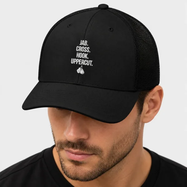 Casquette trucker rétro avec, brodés à l'avant, les mots blancs « JAB. CROSS. HOOK. UPPERCUT. » empilés au-dessus d'une paire de gants de boxe suspendus. – photo studio