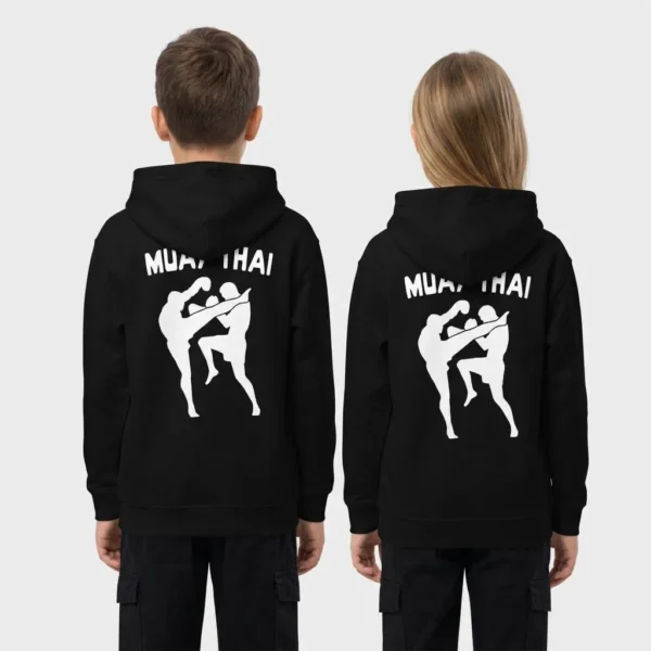 Sweat à capuche enfant avec, imprimées au dos, les silhouettes noires de deux combattants de muay-thaï, l'un en high kick et l'autre bloquant avec le genou, sous le texte « MUAY THAI ». – photo studio