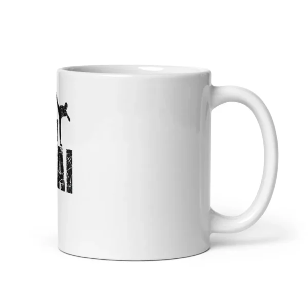 Mug blanc brillant imprimé de la silhouette noire d'un combattant de muay-thaï en high kick au-dessus du lettrage « MUAY THAI » à effet craquelé. (Blanc, mockup principal)