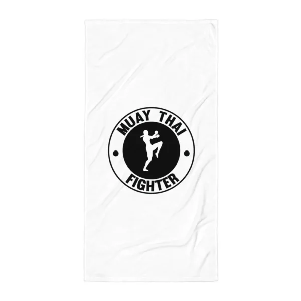 Serviette de plage blanche imprimée d'un badge circulaire représentant une combattante de muay thaï en garde, genou levé, entourée du texte « MUAY THAI FIGHTER ». (Blanc, mockup principal)