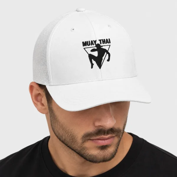 Casquette trucker avec arrière en filet, brodée sur le devant d'une silhouette noire de combattant de muay-thaï au mongkol donnant un coup de genou sauté devant un triangle inversé, sous l'inscription « MUAY THAI ». – photo studio